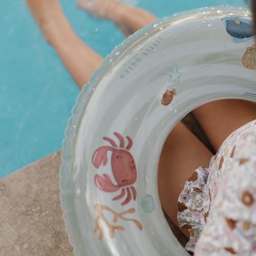 Boia insuflável transparente com desenhos de caranguejo e estrelas do mar perto de piscina.