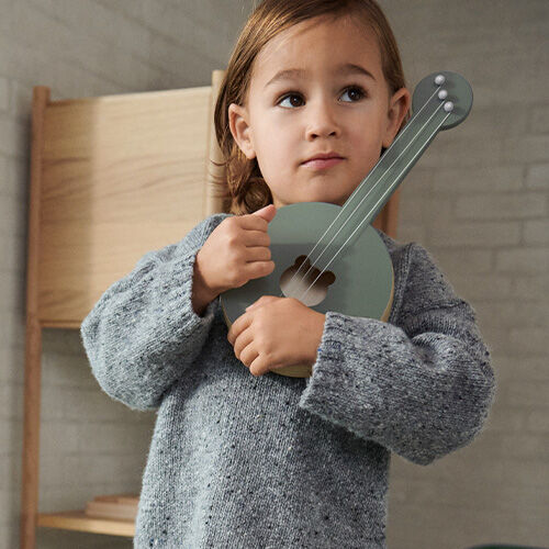 Criança a segurar banjo cinza em ambiente interior