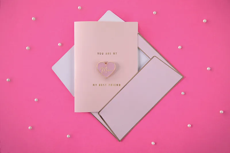 Cartão cor-de-rosa com envelope e corações em relevo, fundo rosa com pérolas