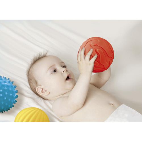 Bebé deitado segurando bola vermelha com duas bolas coloridas ao lado