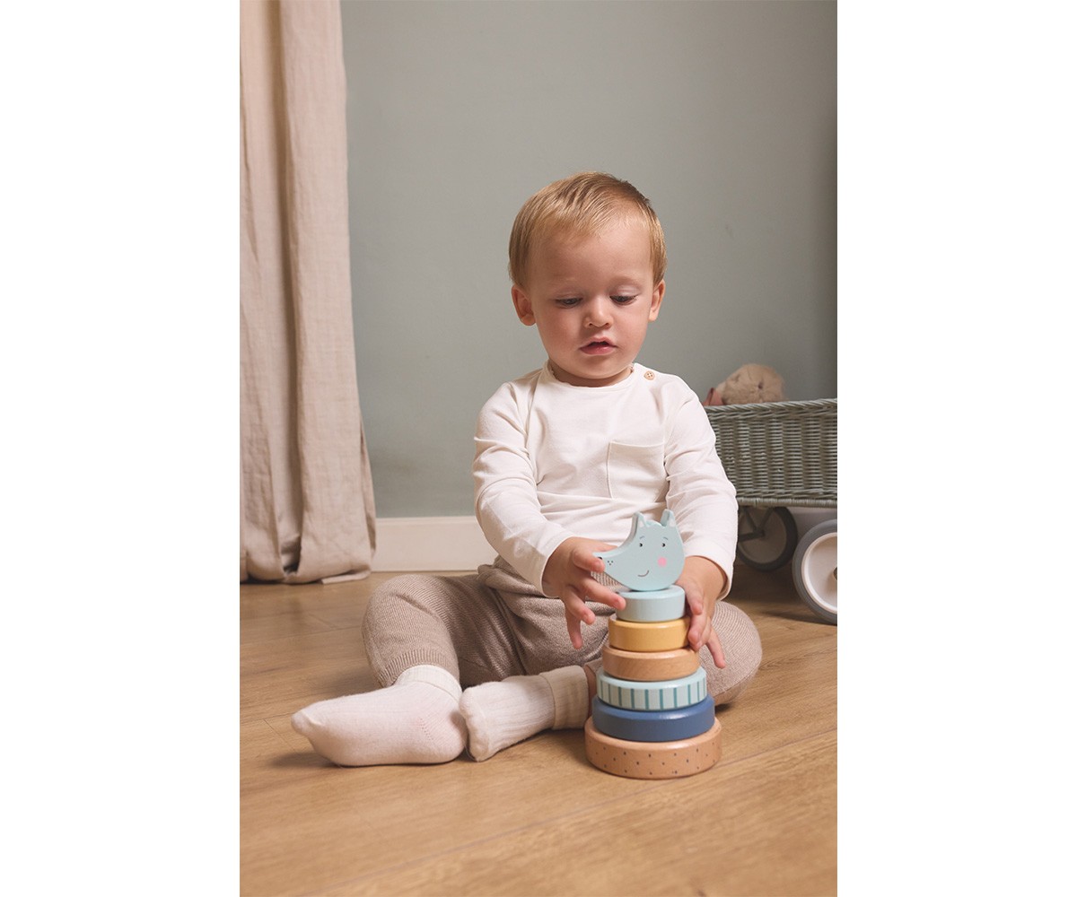 Bebé a brincar com brinquedo empilhável colorido no chão de madeira