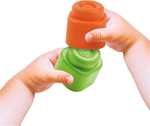 Mãos de criança segurando blocos de montar de plástico laranja e verde.