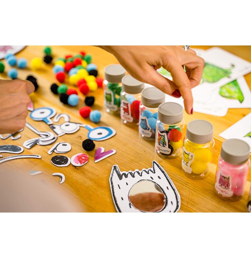 Frascos pequenos com pompons coloridos e recortes de papel sobre mesa de madeira