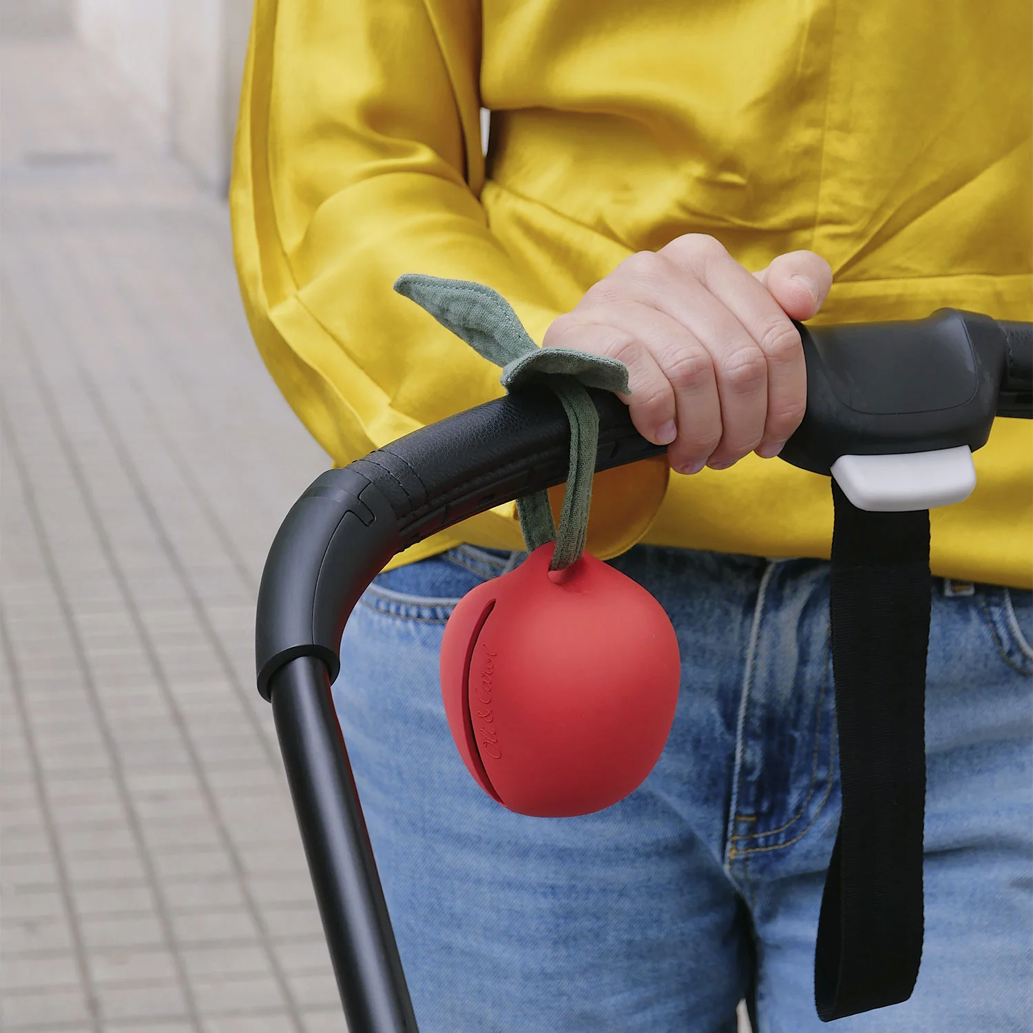 Carrinho de bebé preto com acessório de maçã vermelha pendurado no punho
