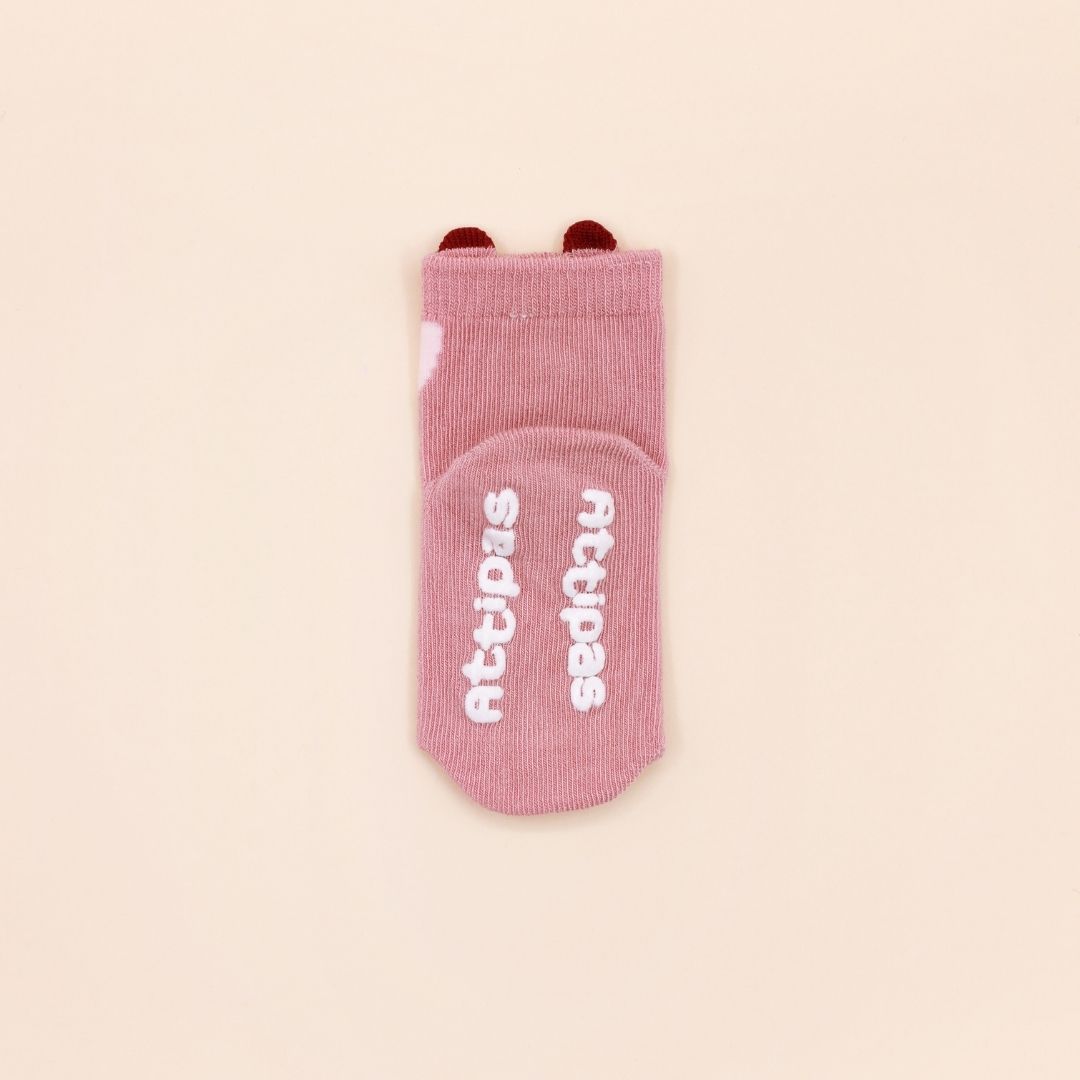 Meias infantis cor-de-rosa com texto branco na sola e detalhes vermelhos no topo