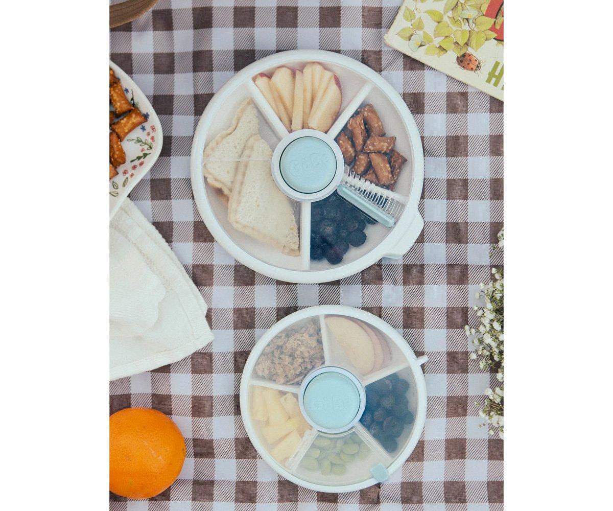 Recipientes circulares de plástico com petiscos em cima de toalha xadrez