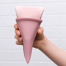 Concha menstrual rosa segurada por mão em fundo branco