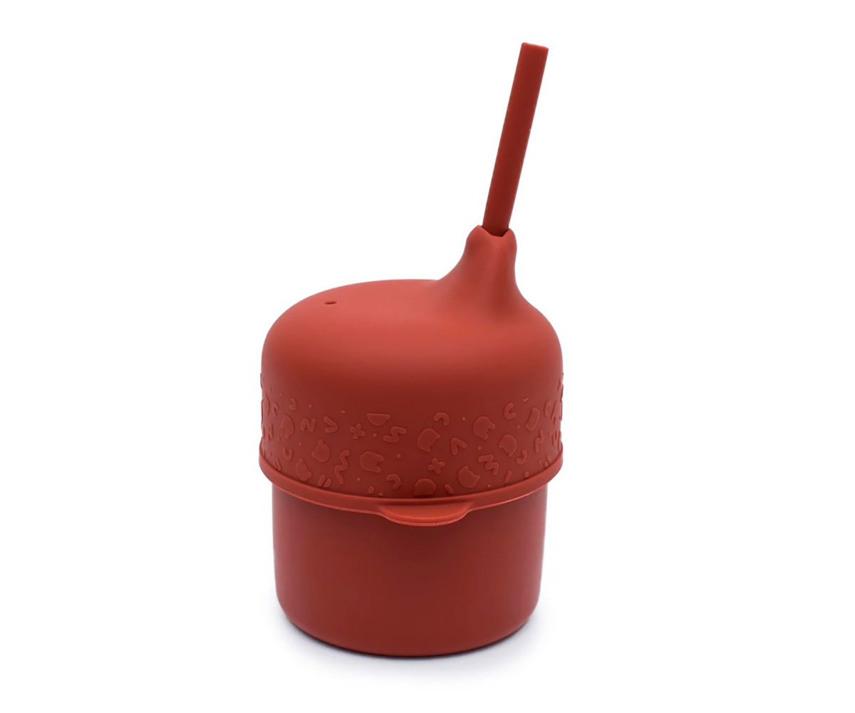 Recipiente vermelho de silicone para bebés com tampa, bico e canudo, fundo branco.