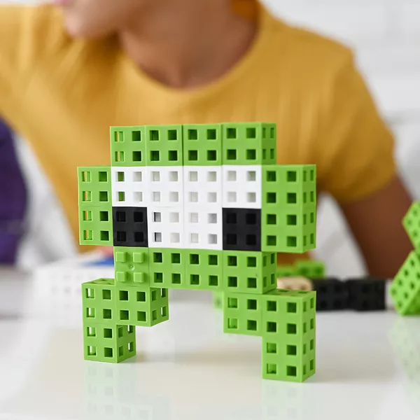Figura de brinquedo feita de blocos verdes, brancos e pretos em superfície branca