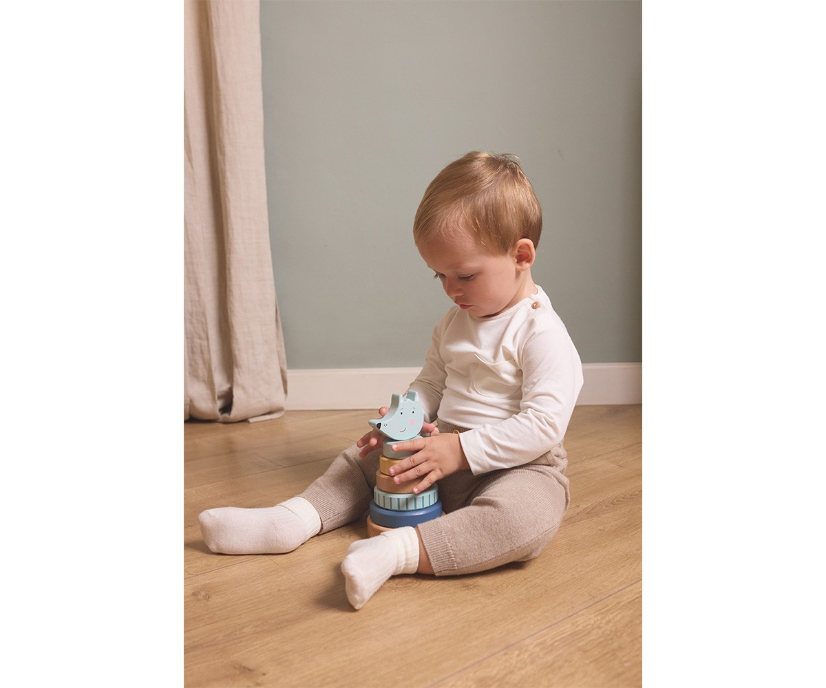 Criança sentada brincando com brinquedo empilhável de madeira colorida