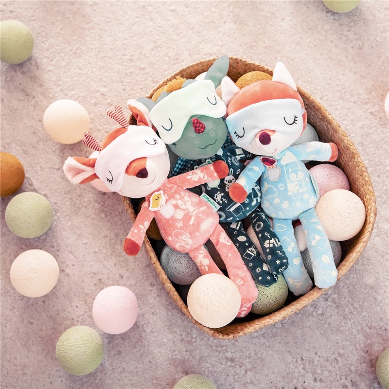 Três bonecos de pelúcia em forma de animais coloridos numa cesta com luzes de bolas coloridas