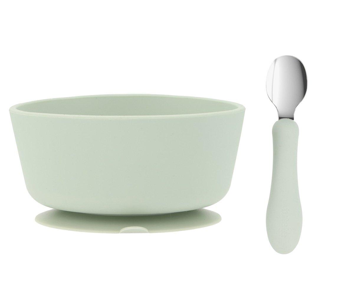Tigela verde claro com base antiderrapante e colher com pega verde claro e parte superior metálica