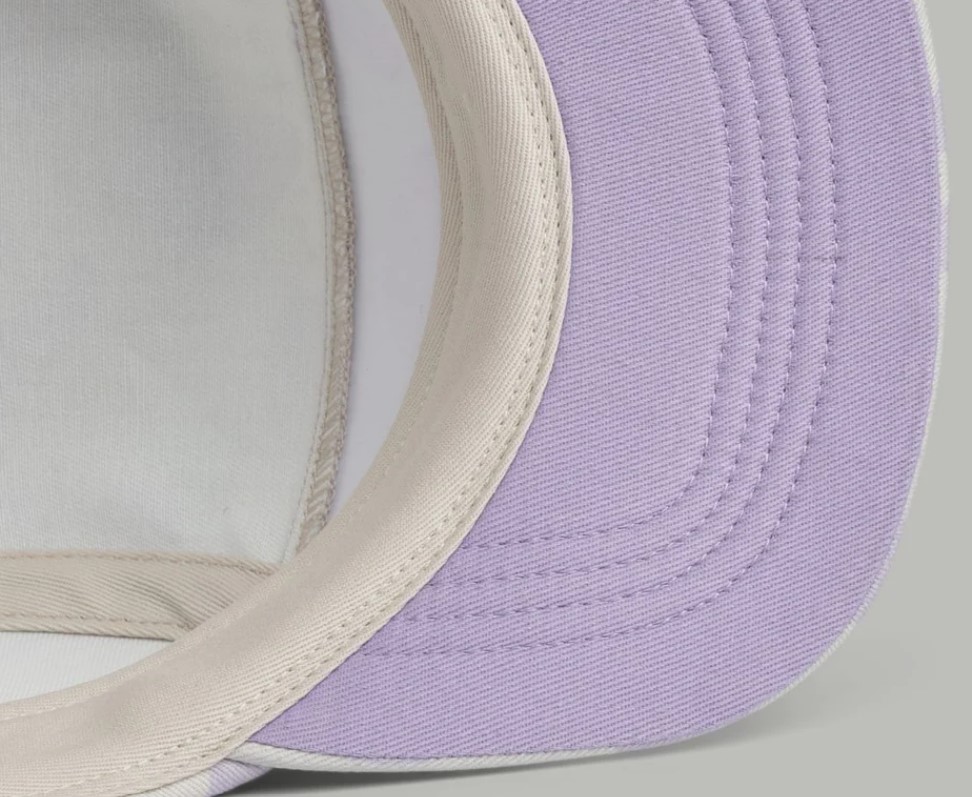Aba lilás e interior bege e branco de um boné com costuras