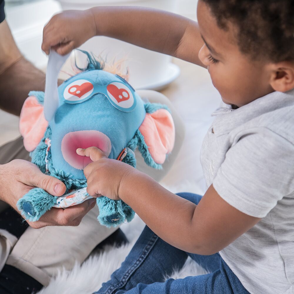 Criança a brincar com peluche azul com orelhas cor-de-rosa e olhos desenhados