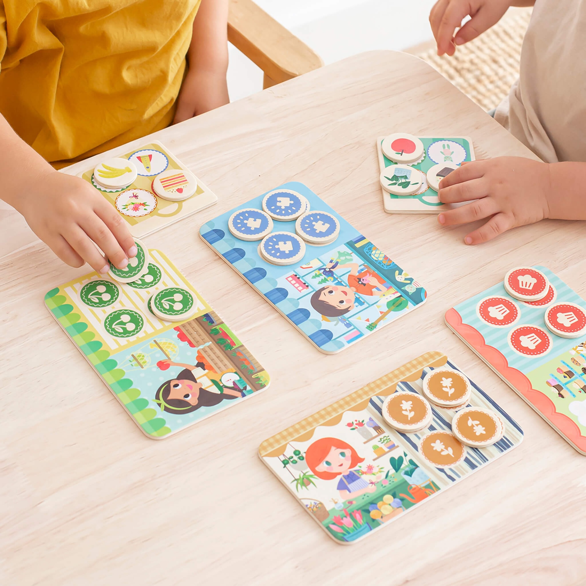 Jogo infantil de cartas com desenhos coloridos e tokens circulares na mesa