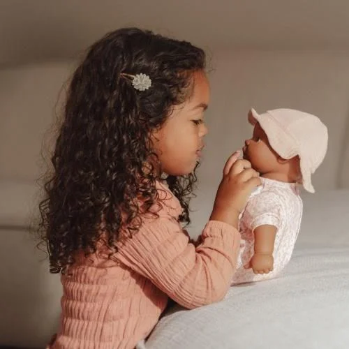 Menina a brincar com boneco bebé vestido de branco