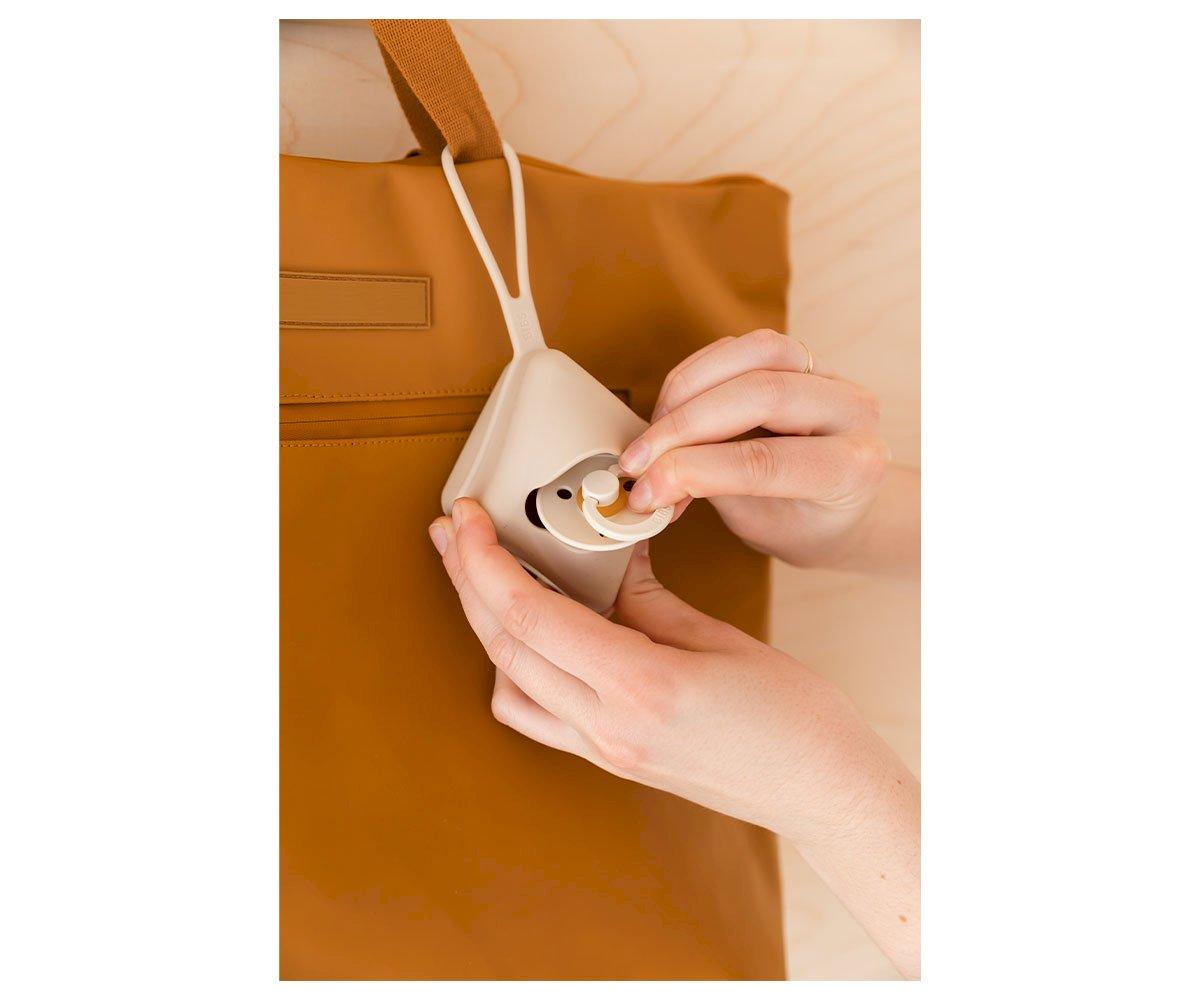 Fones de ouvido brancos em estojo cinza pendurados em bolsa castanha clara