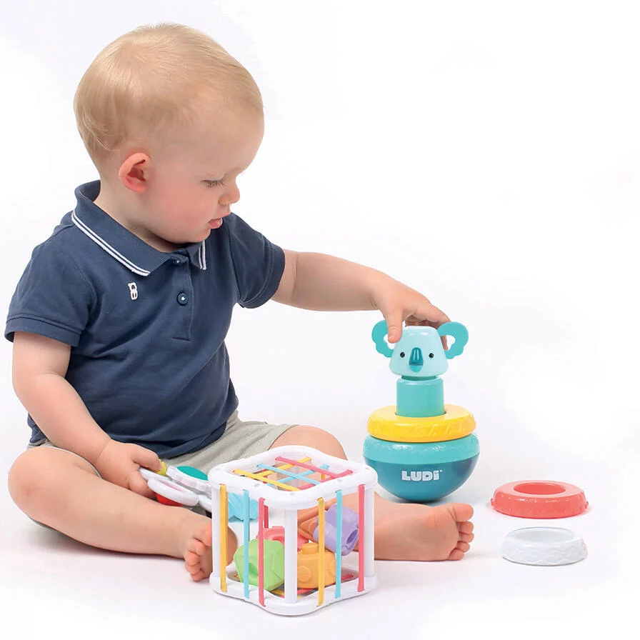 Bebé sentado a brincar com brinquedos coloridos de plástico branco e azul