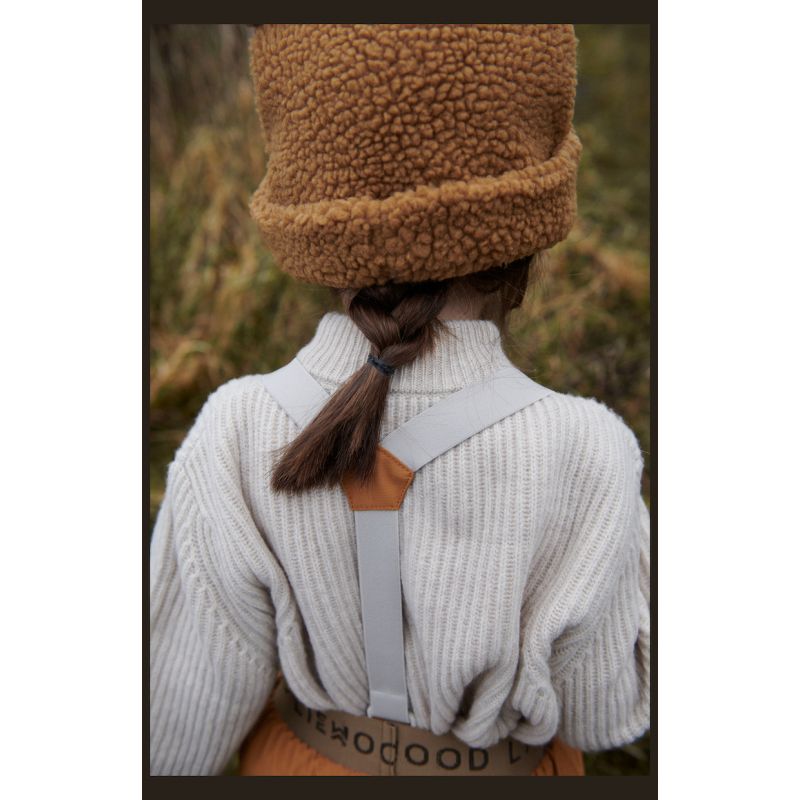 Criança de costas com camisola branca e chapéu castanho peludo