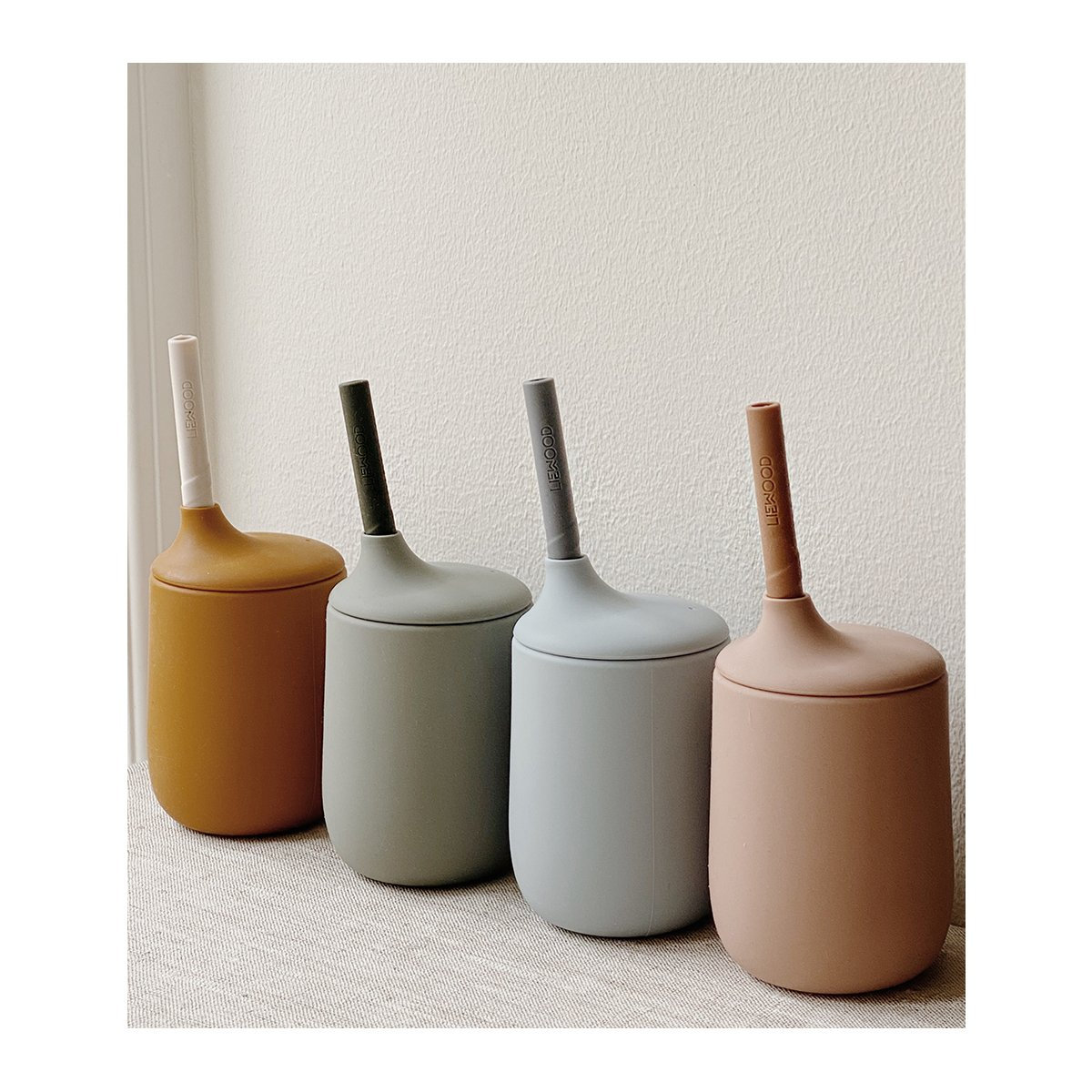 Quatro escovas sanitárias com suporte em cores neutras sobre superfície clara