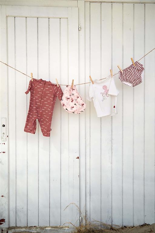 Roupas de bebé penduradas num varal contra uma porta branca