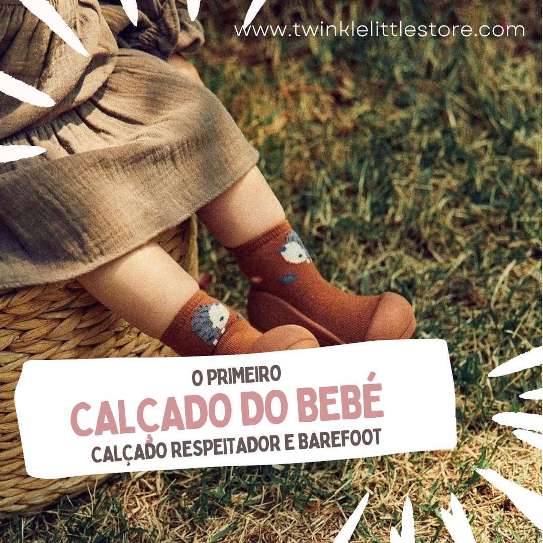 Bebé com meias castanhas com ovelha e sapatos castanhos sentado num cesto sobre relva.