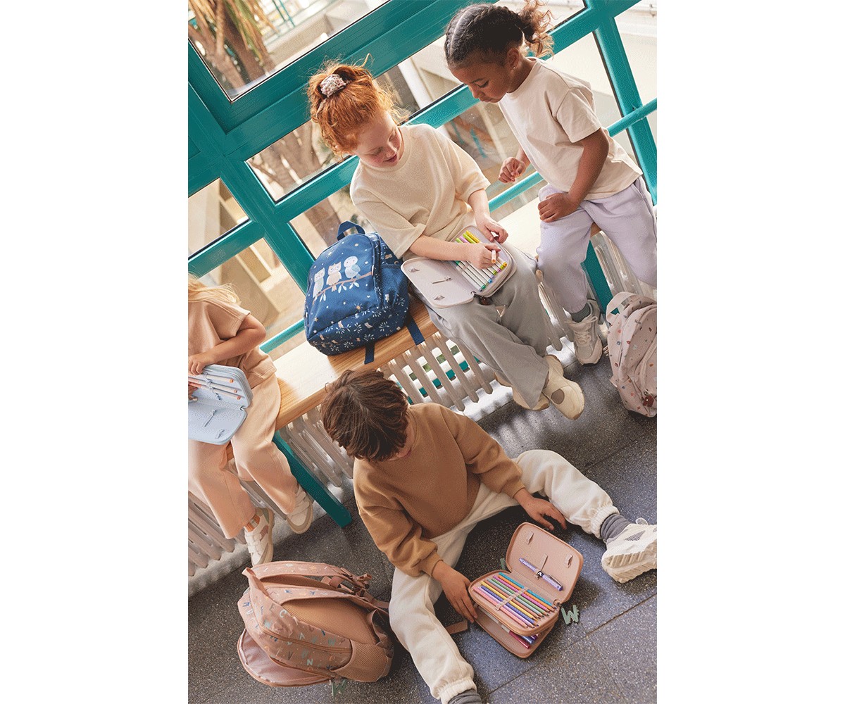 Crianças sentadas com mochilas coloridas e material escolar aberto