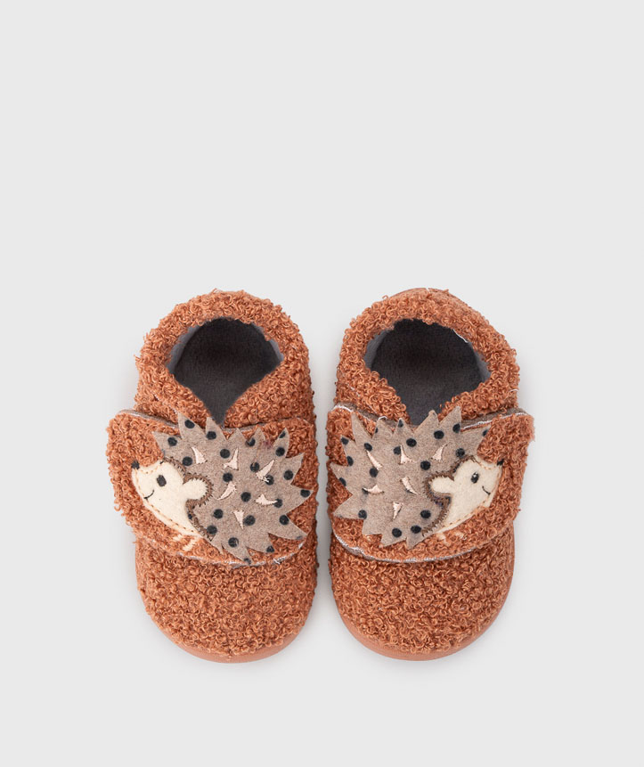 Sapatinhos de bebé castanhos com leões decorativos cinzentos e pretos.