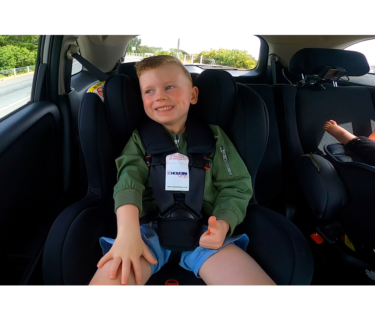 Criança sentada em cadeira auto preta dentro de um carro