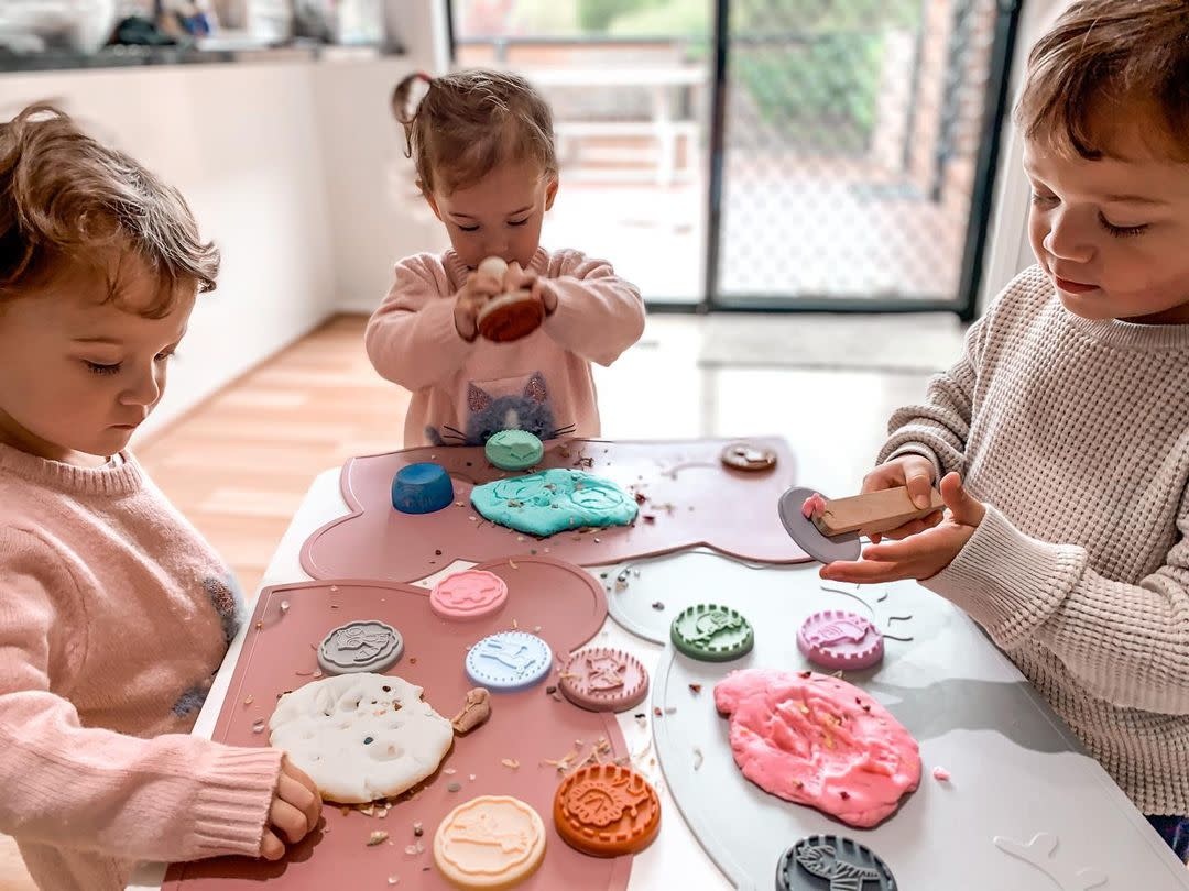 Crianças a brincar com massa de modelar colorida em mesas com bases em forma de coelho