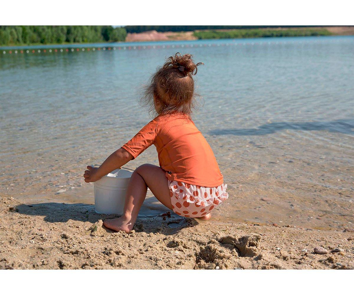Criança numa praia com balde branco