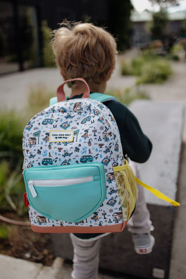 Mochila infantil colorida com bolso frontal turquesa e bolso lateral amarelo, vista traseira de uma criança a usar.