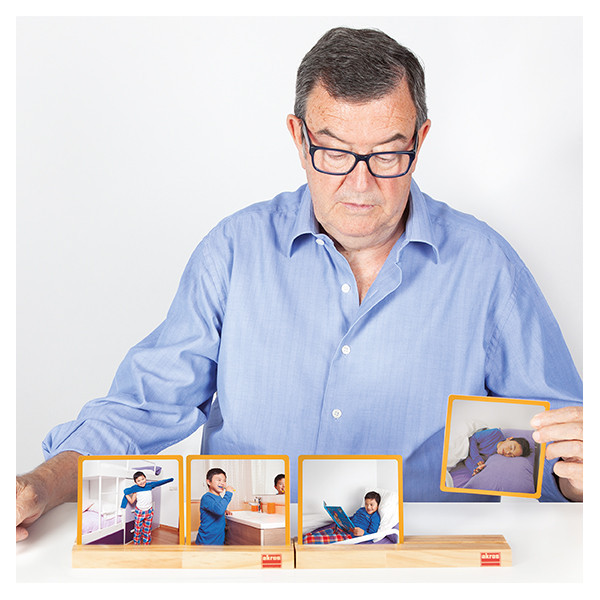Homem com camisa azul sentado a mostrar conjunto de fotografias de criança em suportes de madeira