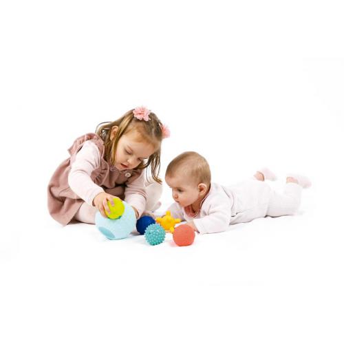 Duas crianças a brincar com bolas coloridas num fundo branco