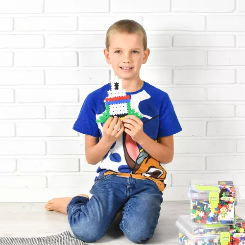 Menino sentado no chão a segurar uma construção de peças plásticas coloridas em forma de farol.