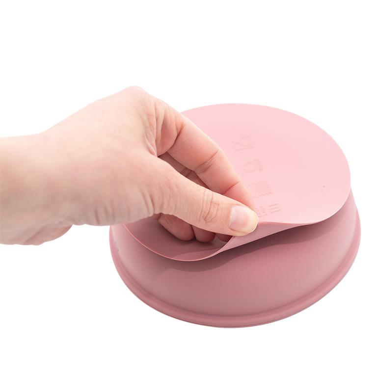 Tampa de silicone cor-de-rosa a ser retirada de recipiente redondo cor-de-rosa