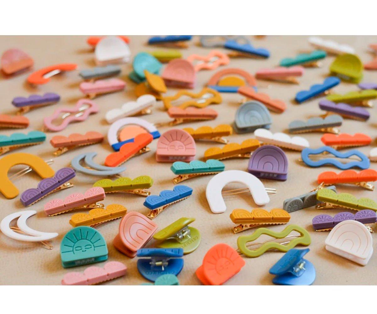 Brincos coloridos em diversas formas sobre superfície neutra