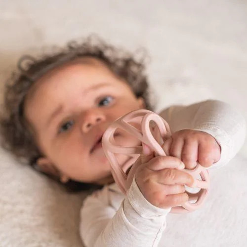 Bebé a segurar brinquedo de silicone rosa