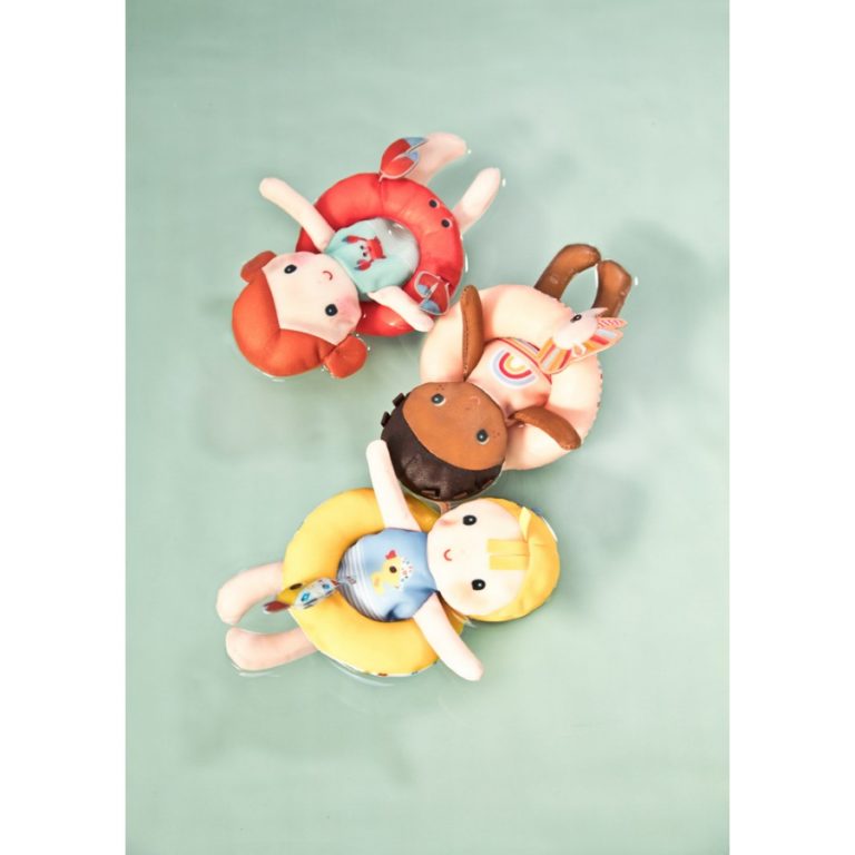 Três bonecas de pelúcia coloridas deitadas numa superfície azul clara