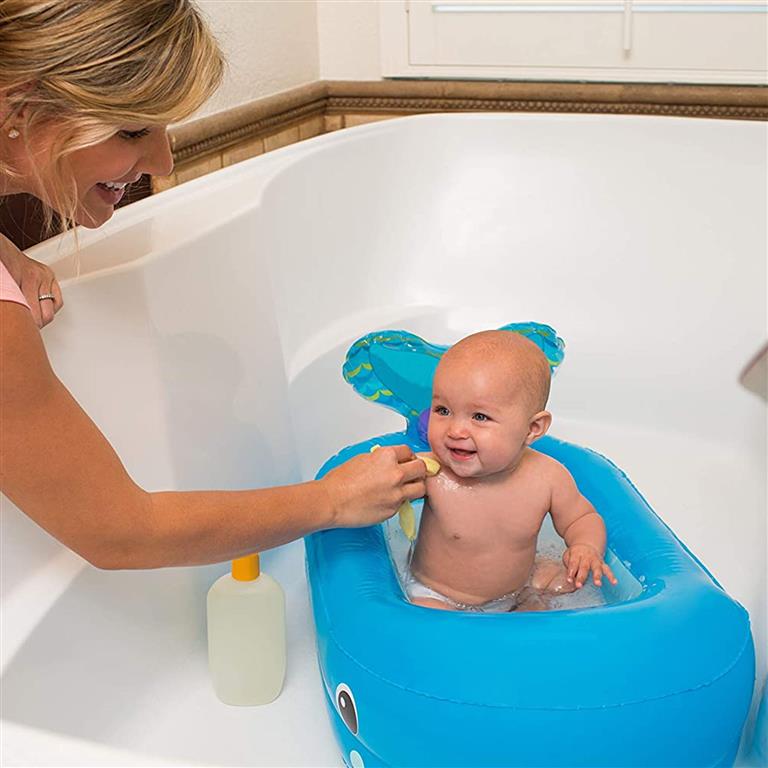 Banheira insuflável azul com bebé sentado e mulher loira interagindo na banheira branca