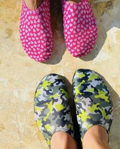 Dois pares de sapatilhas aquáticas, uma rosa com corações brancos e outra camuflada em cinzento, preto e verde