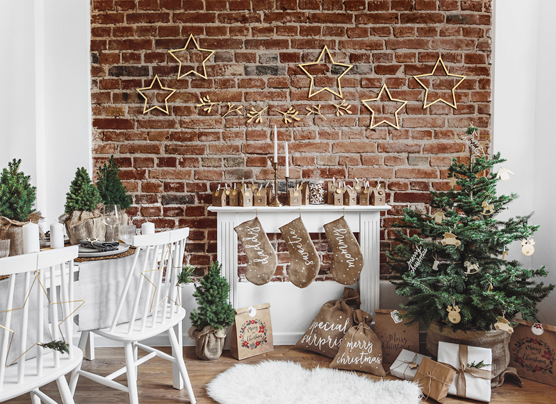 Sala de Natal com meias penduradas, árvores de Natal e decoração rústica e natural.