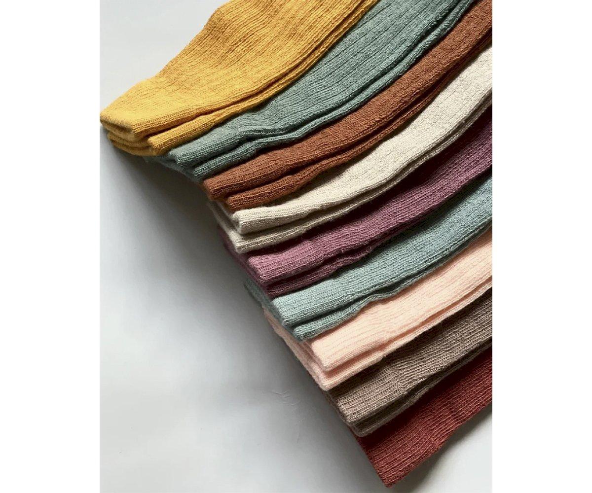 Nove peças de tecido de cores diferentes dobradas sobre fundo branco