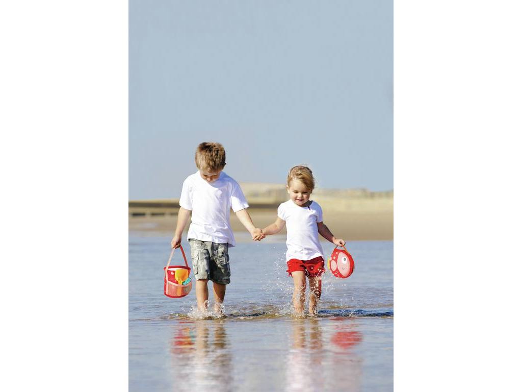 Duas crianças a andar na água na praia a segurar baldes coloridos.