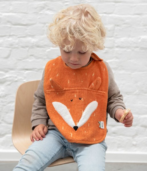 Babete laranja com padrão de raposa numa criança sentada numa cadeira de madeira