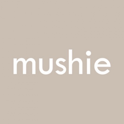 Logotipo branco 'mushie' sobre fundo cinzento-bege