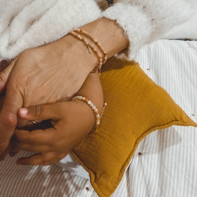 Mãos com pulseiras de contas e almofada mostarda