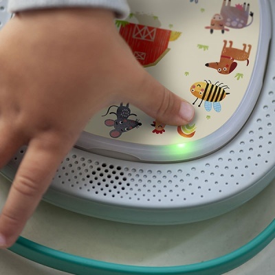 Dispositivo infantil interativo redondo com desenhos de animais e luz verde acesa