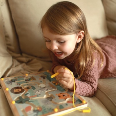 Criança a brincar com tabuleiro de madeira colorido sobre sofá bege