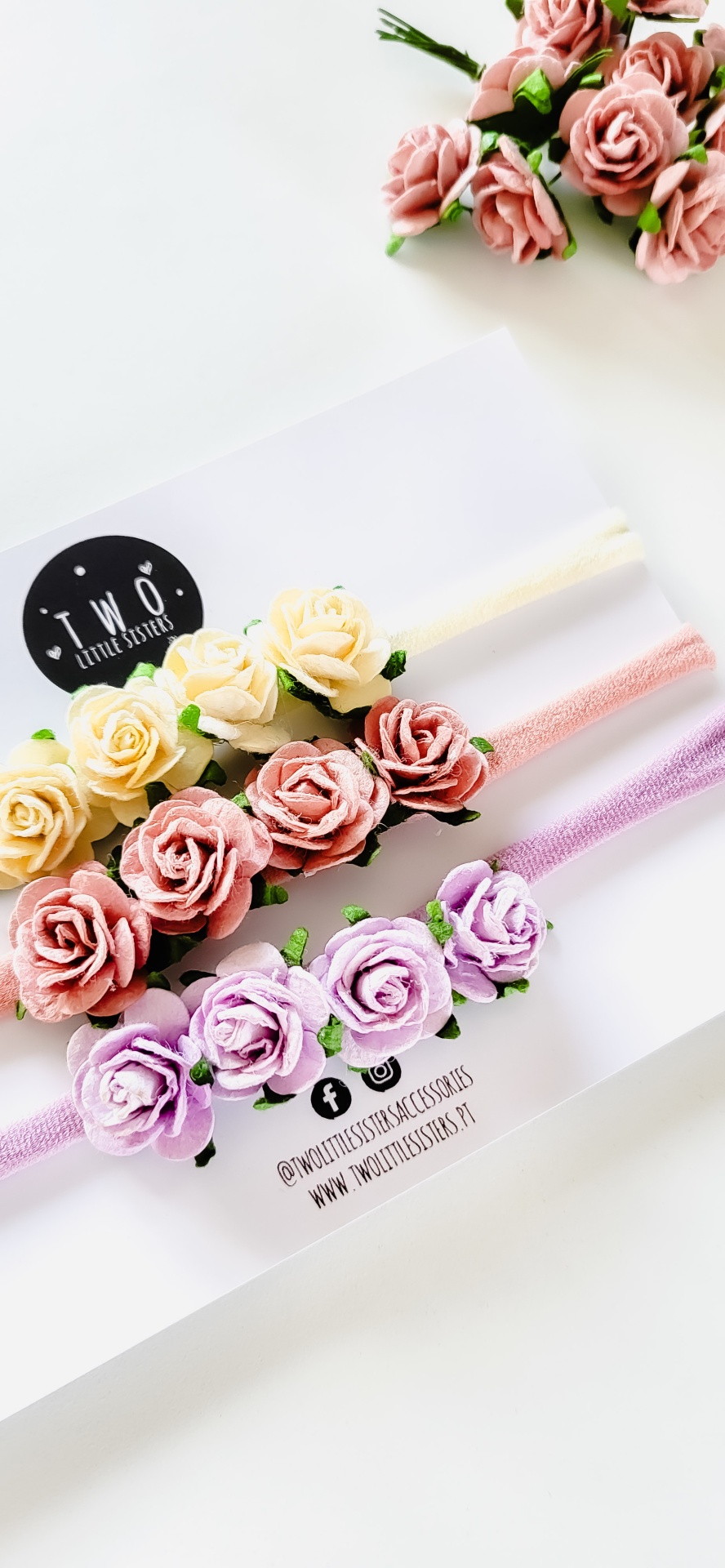 Três faixas para cabelo coloridas com flores de tecido em amarelo, rosa e lilás sobre cartolina branca